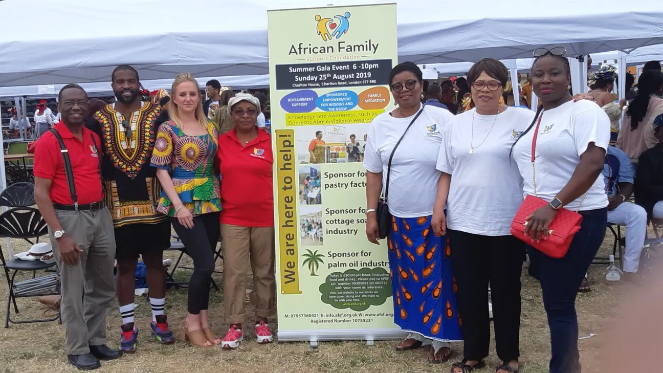 A group of people, including foundation staff and community members, standing next to an AFSF banner at an outdoor Summer Gala event.